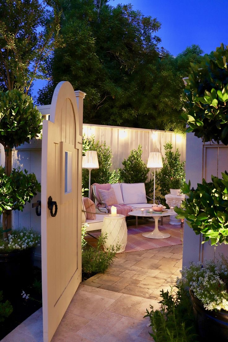 an outdoor living area with a white gate, fence, hardscape, and landscape 